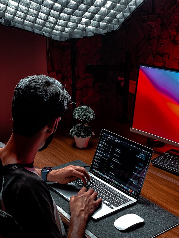 A man working on a laptop in a modern and stylish indoor workspace with ambient lighting.